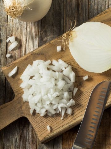top view of chopped onions and a knife on a wood cuttingboard