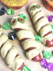 hot dogs wrapped in bread strips to look like mummy dogs with green olives as eyes