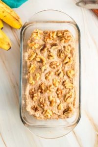top view of a loaf pan with the banana bread batter and topped with walnuts