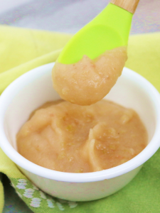 bowl of applesauce with a green spoon taking a scoop