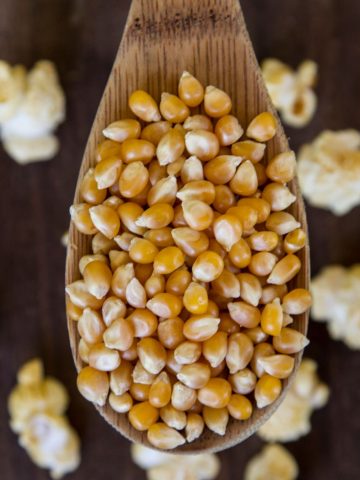top view of a wooden spoon filled with popcorn kernels