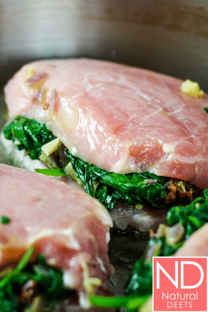 raw pork chops stuffed with sauteed spinach placed in a saute pan