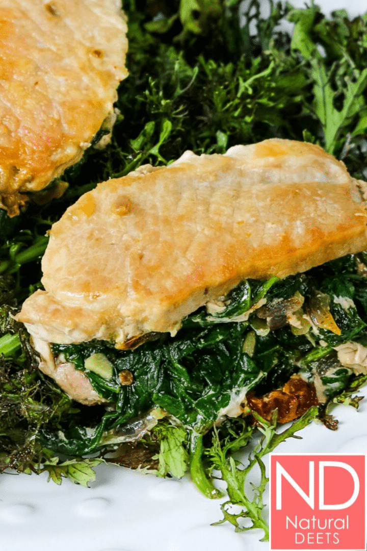 a picture of pork chops stuffed with spinach on a plate of mustard greens