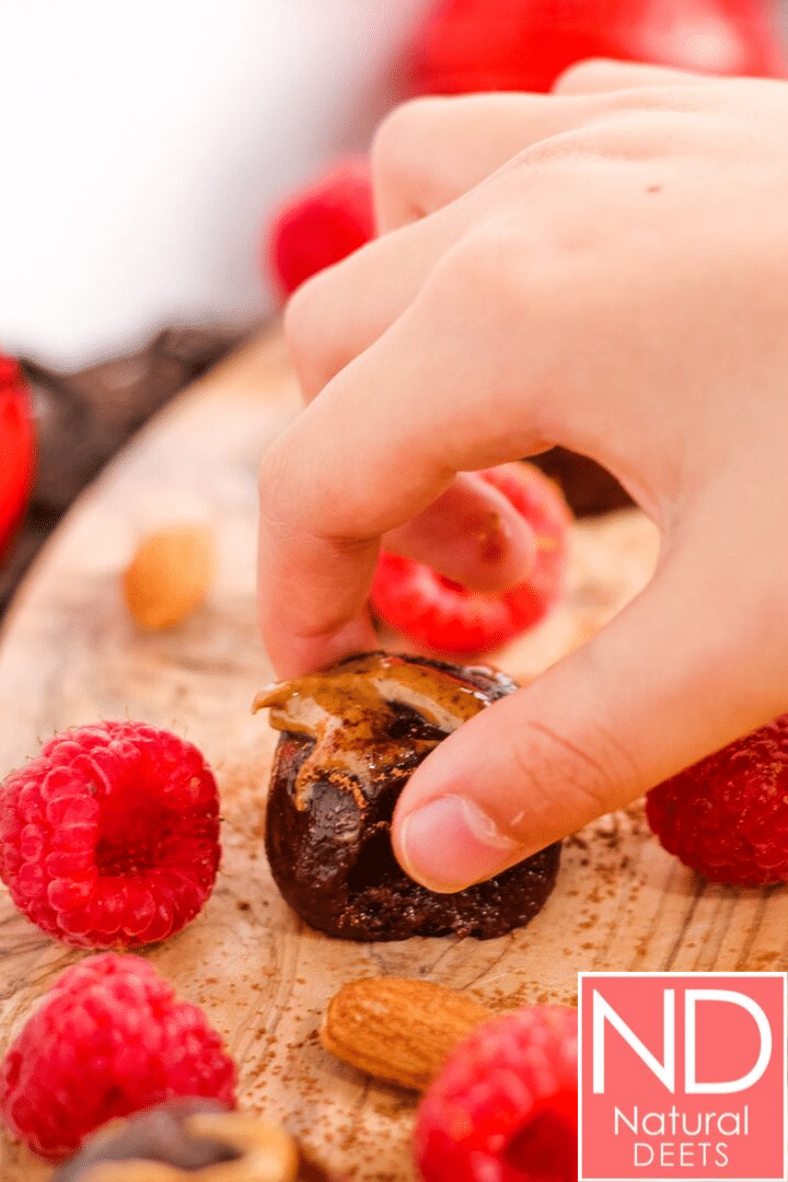 vertical picture of a kids hand grabbing a chocolate energy ball