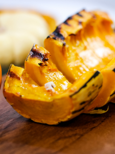 half of a delicata squash sliced and placed on a cutting board