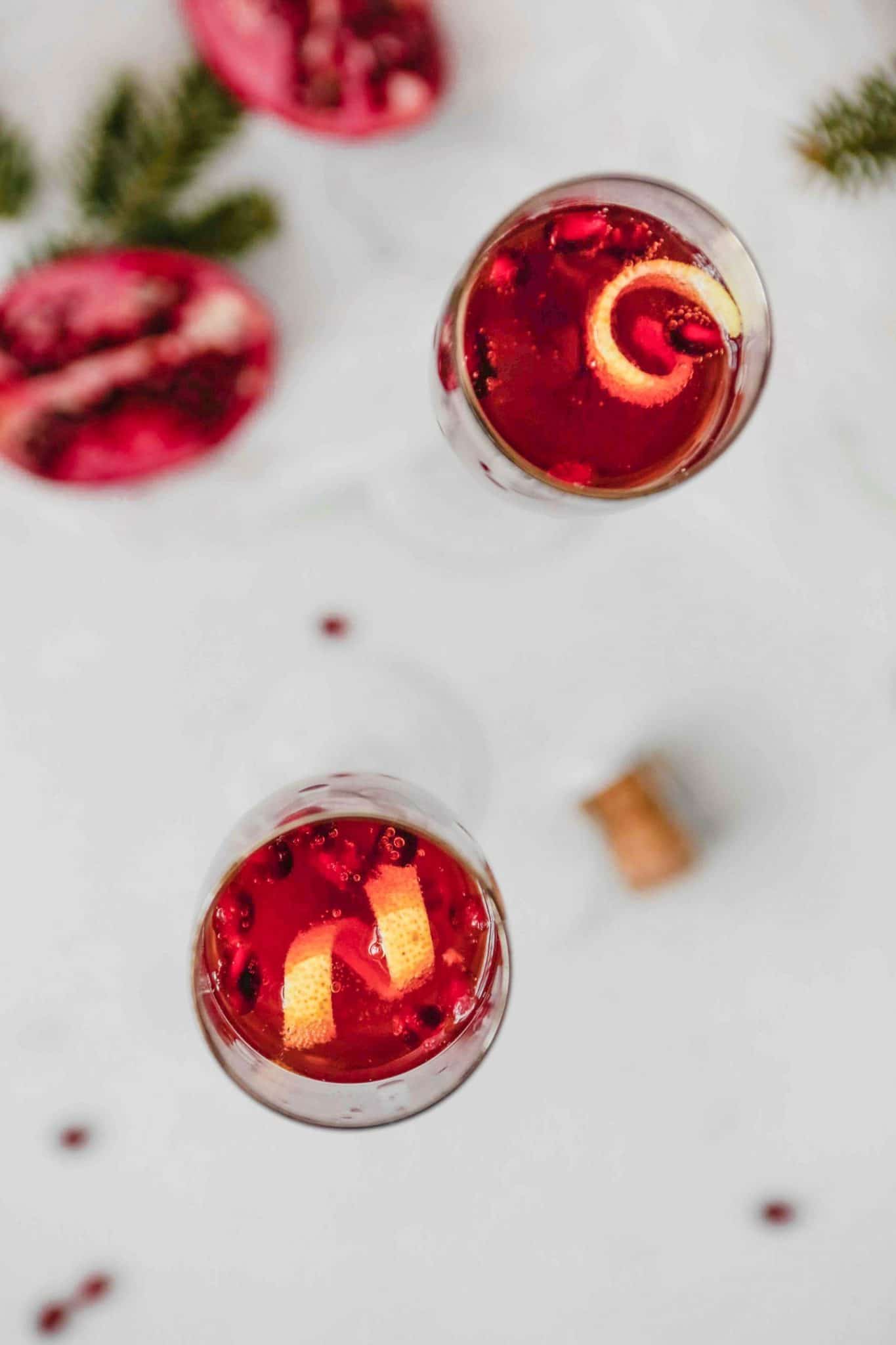pomegranate kir royale in a champagne glass with orange peel spirals