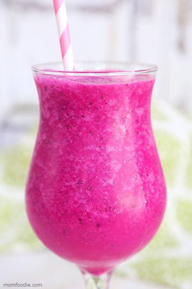 close up side view of a bright pink smoothie in a glass cup