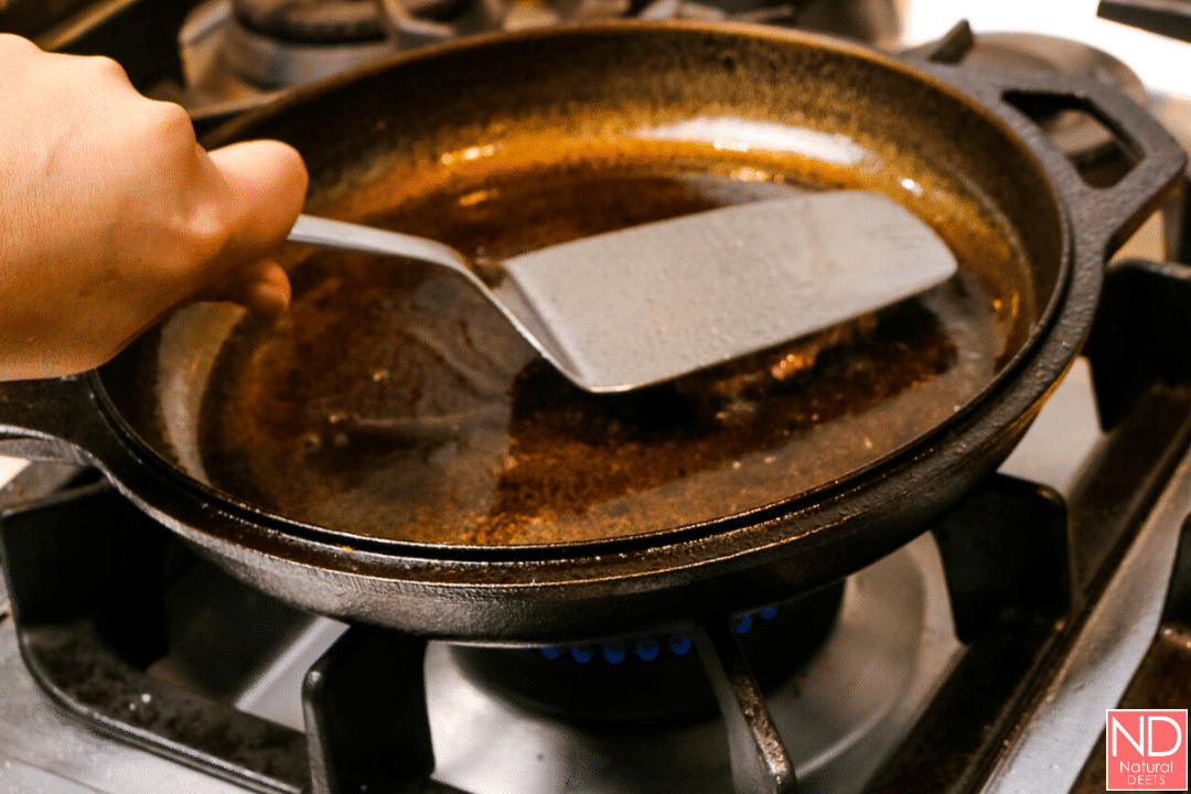 a picture of a spatula smashing a hamburger patty in a cast iron skillet