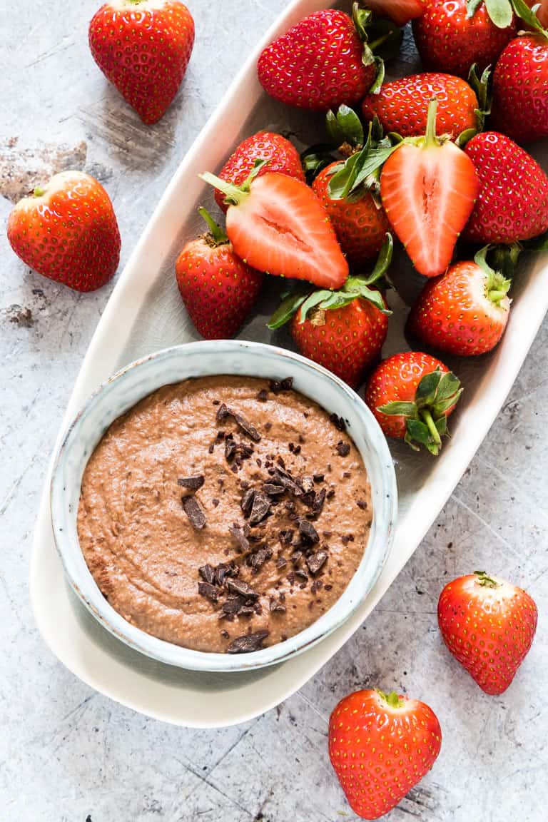 a white tray with fresh strawberries and a bowl of chocolate hummus dip