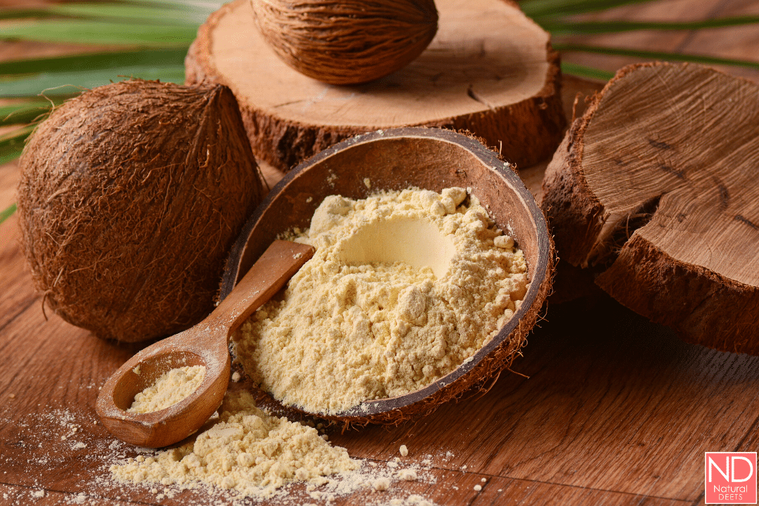 a picture of coconut flour on a wooden spoon next to a coconut