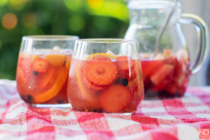 two glasses filled with red sangria and fruits