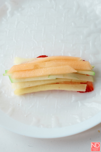 cantaloupe and honeydew matchbook slices on a rice paper wrapper