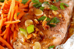 salmon with green onions and shredded carrots on a piece of foil