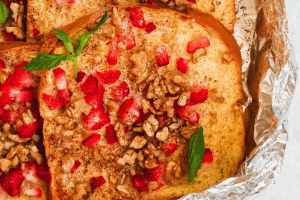 french toast on a piece of foil with pomegranates and nuts sprinkled on it