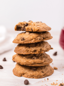 a stack of 5 chocolate chip cookies and the top one has a bite