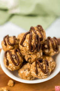 energy balls stacked in a small bowl with chocolate drizzle