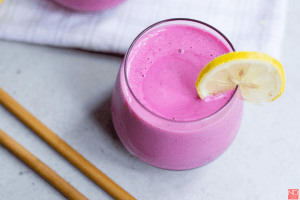 a top view of a dragon fruit smoothie on a table with a straw and lemon slice