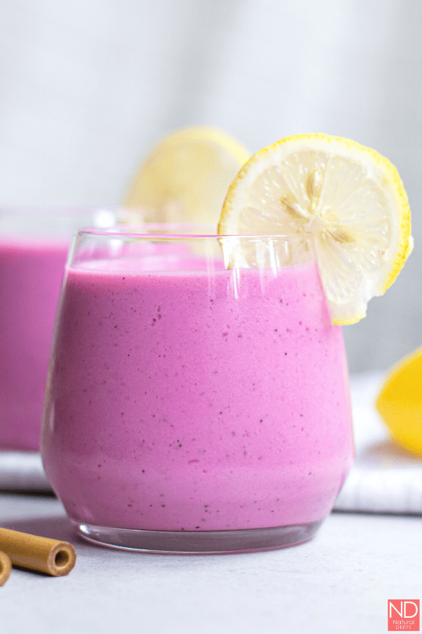 a side view of a dragon fruit smoothie in a short cup with a lemon slice