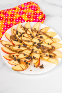 a plate of sliced apples drizzled with almond butter and sprinkled with mini chocolate chips