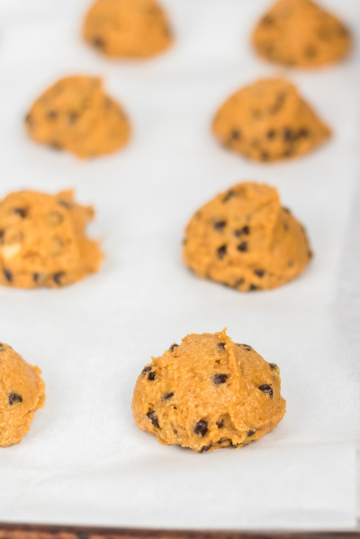 pumpkin cookie dough in lines on a parchment paper lined sheet pan