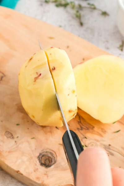 a peeled potato with a small knife cutting it into a 1/2 inch slice