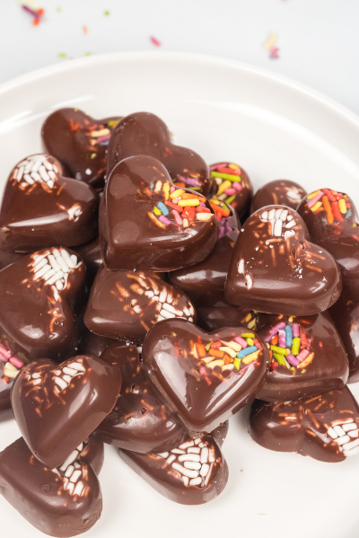 a white plate with Chocoalte hearts covered in sprinkles