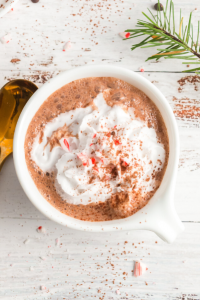 top view of a white mug with hot chocolate, whipped cream and crushed candy canes