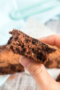 side view of a brownie with a bite and a hand holding it