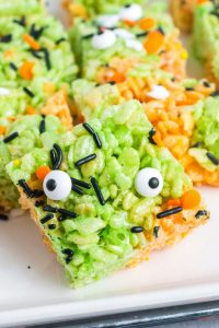 green and orange rice krispy square with black and orange sprinkles and two eye ball candies
