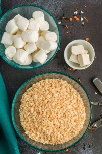 top view of a bowl of rice krispies, a bowl of marshmallows and a bowl of butter