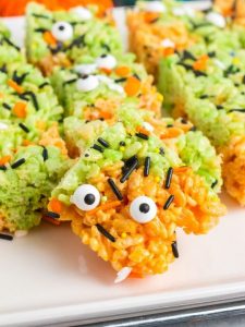 side view of a orange and green rice crispy treat with candy eyes and spirnkles