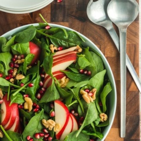 top view of a spinach pear salad with pomegranate and walnuts