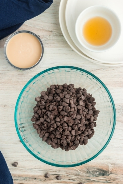 top view of a bowl of chocolate chips, a bowl with condensed milk and a bowl with vanilla