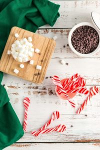 top view of candy cane spoons, a bowl of chocolate chips and a bowl of marshmallows