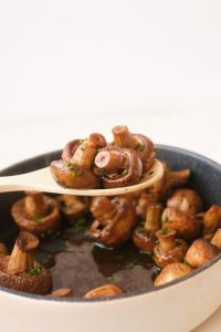mushrooms in a white pan held up on a spoon