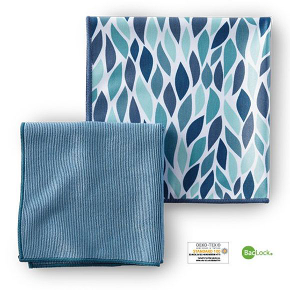 two cloths folded into squares. One is teal and one is white with leaves of different shades of blue