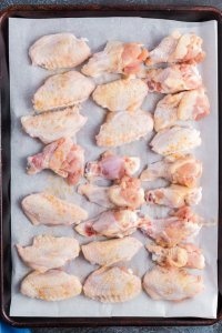 raw chicken wings on a sheet pan lined with parchment paper