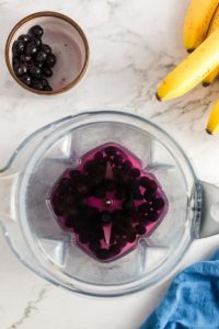 top view of a blender container with blueberries and water