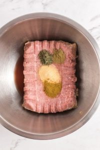 a rectangle ground turkey in a metal bowl with spices on it