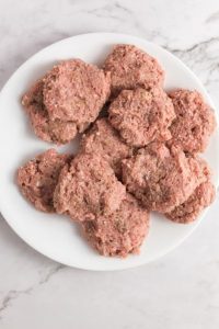 top view of raw sausage patties on a white plate