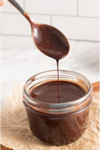 side view of a glass with chocolate sauce and a spoon dripping chocolate sauce