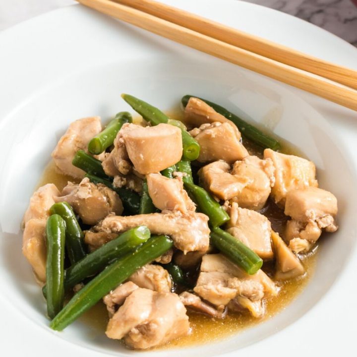Side view of the chicken and green beans in a white bowl