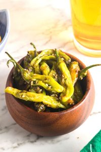 side view of green sauteed peppers in a wooden bowl