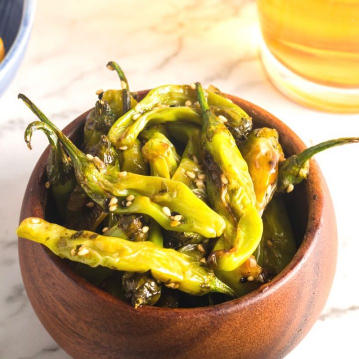 side view of green sauteed peppers in a wooden bowl