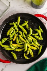 top view of black round grill pan with green peppers in it