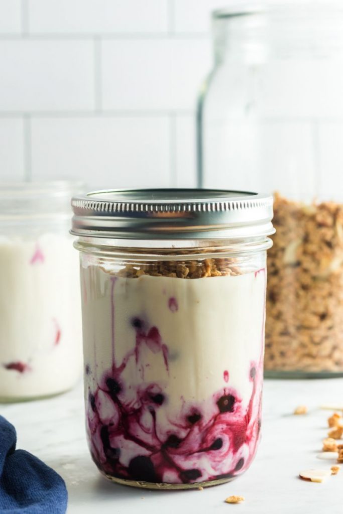 side view of a glass mason jar with blueberries on the bottom and yogurt on top