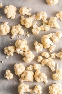 top view of cauliflower florets on a sheet pan with parchment paper