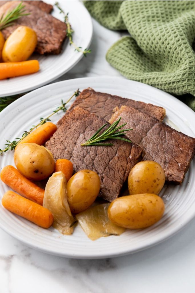 roast slices on a plate with baby potatoes and carrots