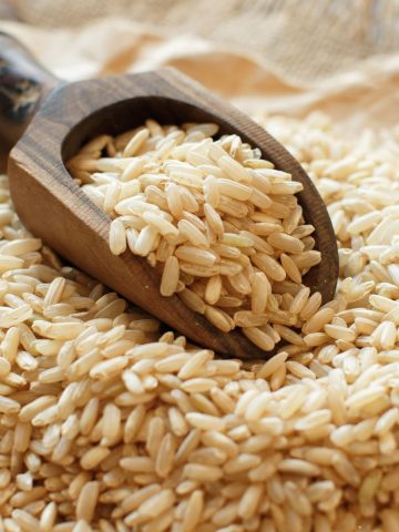 a brown scoop with raw brown rice in it